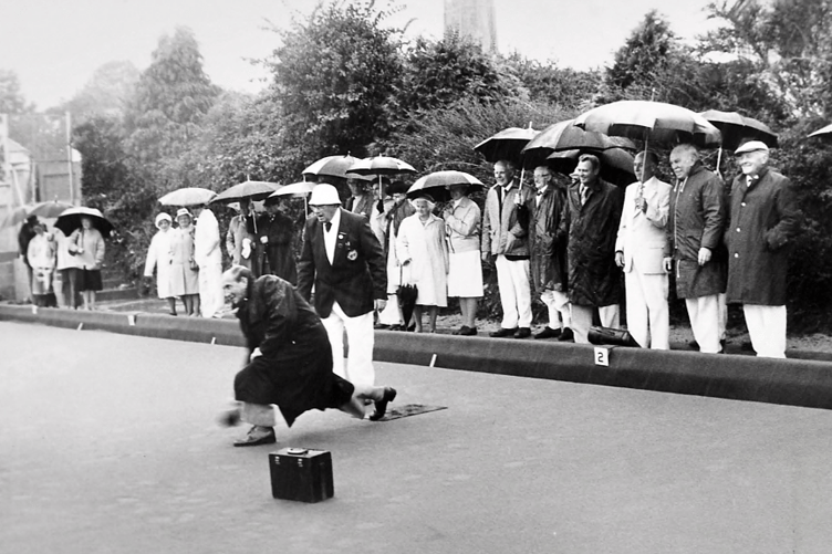 Cllr Arthur Bladon bowls the first wood at the official opening of Ipplepen’s new artifical green on a suitably wet day in November 1981.