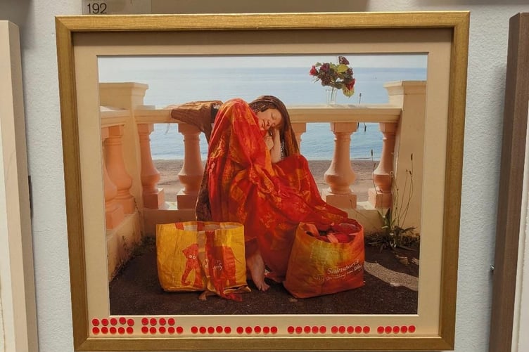 Teignmouth artist Anna Grayson's photo 'Flaming June the Bag Lady' with rows of 'sold' stickers at the Royal Academy.